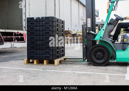 The worker loading pallet with a forklift into a truck. Stock Photo