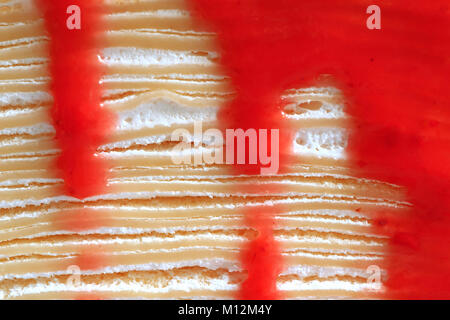 The Texture of Crepe Cake's Layers with Fresh Cream and Flowing Vibrant Red Raspberry Sauce Stock Photo