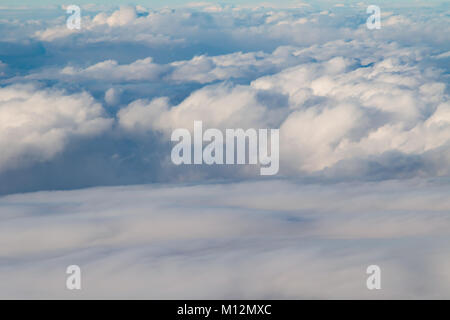Rolling fluffy clouds coming together to for a cloud blanket in the blue sky Stock Photo