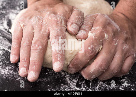 Male hands kneading dough, baking preparation closeup. Stock Photo