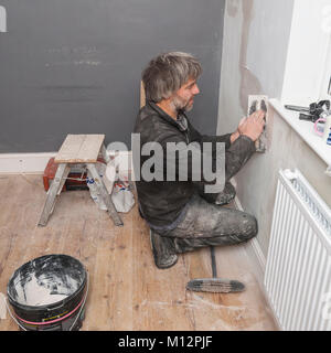 A man plastering some cracks in a wall in the Uk Stock Photo