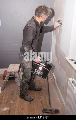 A man plastering some cracks in a wall in the Uk Stock Photo
