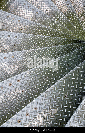 Close up of checker plate metal spiral staircase steps going down Stock Photo