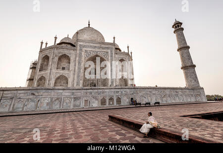Old woman sitting near the pool and enjoying the sunset view of Taj Mahal, Agra, India Stock Photo