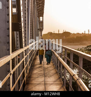 Two Girls walking in railway bridge after work on their way home at sunset, Agra, India Stock Photo