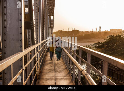Two Girls walking in railway bridge after work on their way home at sunset, Agra, India Stock Photo