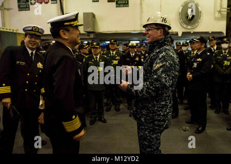 YOKOSUKA, Japan (Jan. 23, 2018) Capt. Buzz Donnelly, commanding officer of the Navy's forward-deployed aircraft carrier, USS Ronald Reagan (CVN 76), exchanges gifts with Vice Adm. Katsuto Deguchi, commandant, Joint Staff College, during a tour in the hangar bay. Ronald Reagan, the flagship of Carrier Strike Group 5, provides a combat-ready force that protects and defends the collective maritime interests of its allies and partners in the Indo-Asia-Pacific region.  (U.S. Navy Stock Photo