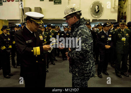 YOKOSUKA, Japan (Jan. 23, 2018) Capt. Buzz Donnelly, commanding officer of the Navy's forward-deployed aircraft carrier, USS Ronald Reagan (CVN 76), exchanges gifts with Vice Adm. Katsuto Deguchi, commandant, Joint Staff College, during a tour in the hangar bay. Ronald Reagan, the flagship of Carrier Strike Group 5, provides a combat-ready force that protects and defends the collective maritime interests of its allies and partners in the Indo-Asia-Pacific region.  (U.S. Navy Stock Photo