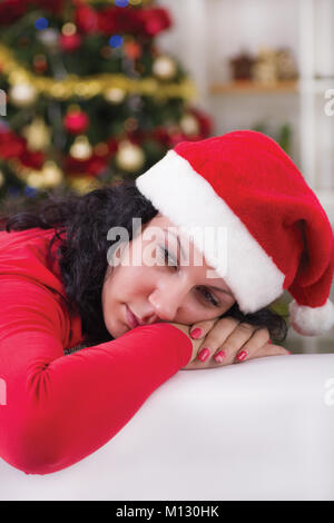 Gorgeous young brunette sitting next Christmas tree looking lonely Stock Photo
