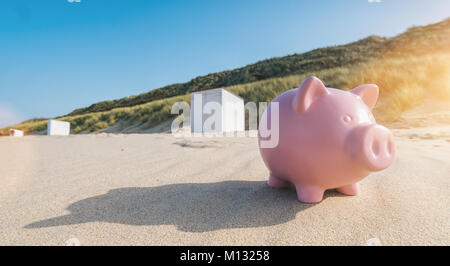 Pink piggy bank on the beach in zeeland at summer. Stock Photo