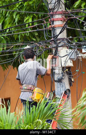 A telephone engineer up on a ladder checking cables Stock Photo