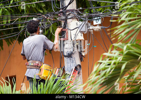 A telephone engineer up on a ladder checking cables Stock Photo