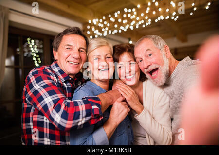 Senior friends with smartphone taking selfie at Christmas time. Stock Photo
