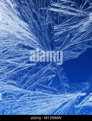 Textures and backgrounds: ice crystals on the window, frost texture over the blue sky gradient. Abstract winter pattern, seasonal background. Stock Photo
