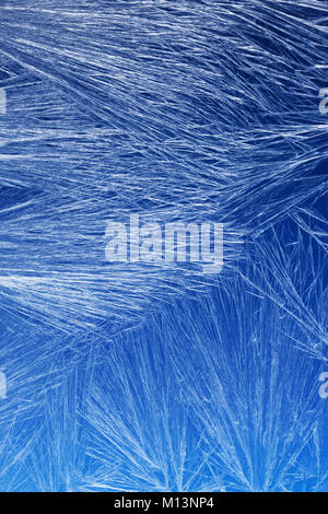 Textures and backgrounds: ice crystals on the window, frost texture over the blue sky gradient. Abstract winter pattern, seasonal background. Stock Photo