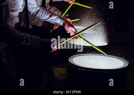 The drum sticks are hitting on the snare drum with splash water in low light background