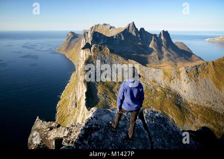 Norway, Troms County, north of the Arctic Circle, Senja island between Tromso and the Lofoten islands, Fjordgard village, trekker at the summit of Segla peak (639m) above the fjord of Mefjord and Oyfjord Stock Photo