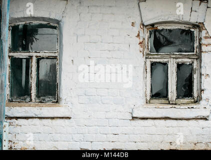 brick wall old rural house with two small old rickety Windows Stock Photo