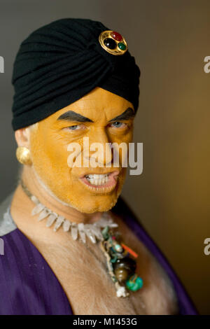 Angry, orange faced man in a purple vest and black turban. Stock Photo