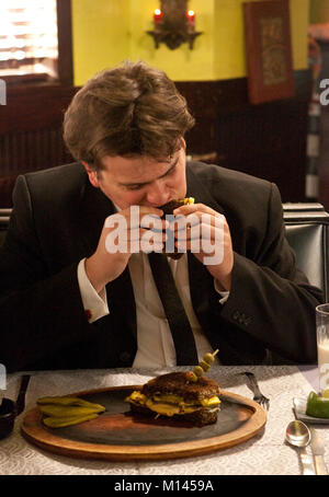 Man sitting in a restaurant booth, eating a sandwich. Stock Photo