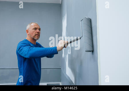 High angle view of a male builder using a roller to paint walls of an interior. Stock Photo