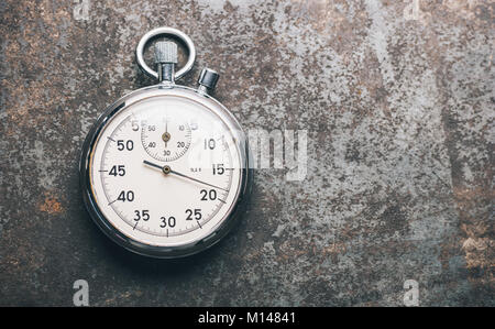 silver stopwatch lies on a weathered background. Stock Photo