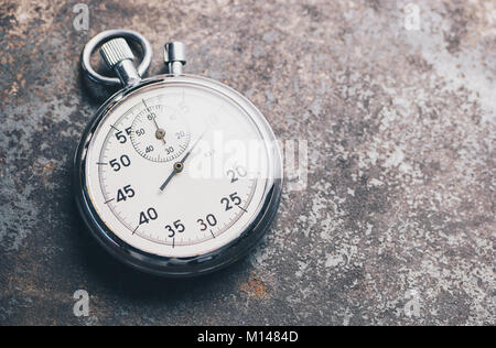 classic silver stopwatch lies on a weathered background. Stock Photo