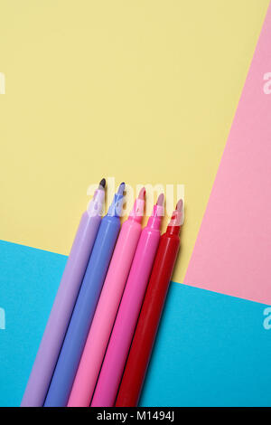 high angle view of some felt pens of different colors on a colorful yellow, pink and blue background, with some blank space on top Stock Photo