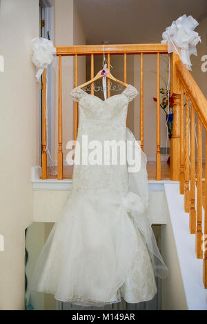 The perfect wedding dress with a full skirt on a hanger in the room of the bride with blue curtains Stock Photo