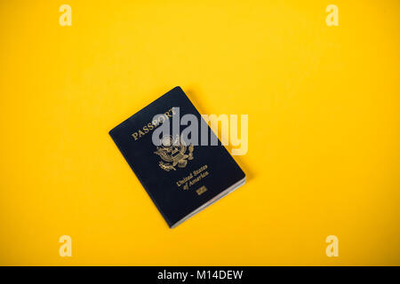 a United States of America passport laying on a yellow backdrop Stock Photo