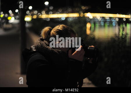 Female photographer takes pictures of a spectacle on the Rhone at night Stock Photo