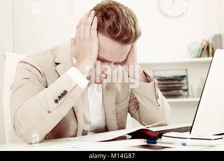 Frustrated young man having business problems with papers at workplace Stock Photo
