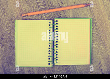 Open notebook lying on wooden surface and pencil Stock Photo