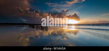 Stormy clouds with sun rays just before sunset on a winters day at West Head on West Wittering Beach Stock Photo