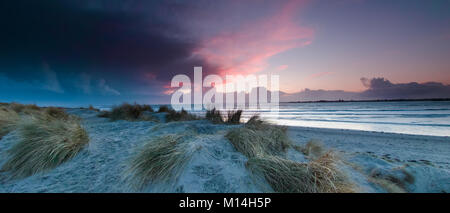 Stormy clouds with sun rays just before sunset on a winters day at West Head on West Wittering Beach Stock Photo