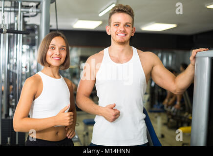 joyful smiling man and woman fitness coaches taking break during workout in gym Stock Photo
