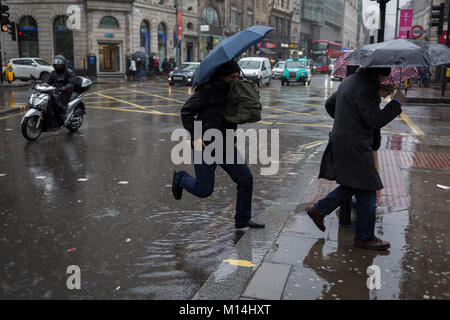 London, 24th January 2018: Storm Georgina swept across parts of Britain and in central London, lunchtime office workers were caught out by torrential rain and high winds. Pedestrians resorted to leaping across deep puddles at the junction of New Oxford Street and Kingsway at Holborn. Credit: Richard Baker / Alamy Live News. Stock Photo