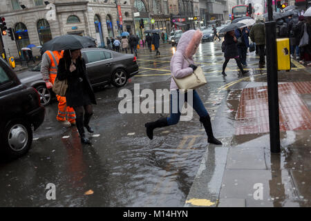 Storm Georgina swept across parts of Britain and in central London, lunchtime office workers were caught out by torrential rain and high winds, on 24th January 2018, in London, England. Pedestrians resorted to leaping across deep puddles at the junction of New Oxford Street and Kingsway at Holborn, the result of overflowing drains. Stock Photo