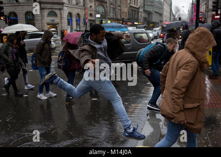 London, 24th January 2018: Storm Georgina swept across parts of Britain and in central London, lunchtime office workers were caught out by torrential rain and high winds. Pedestrians resorted to leaping across deep puddles at the junction of New Oxford Street and Kingsway at Holborn. Credit: Richard Baker / Alamy Live News. Stock Photo