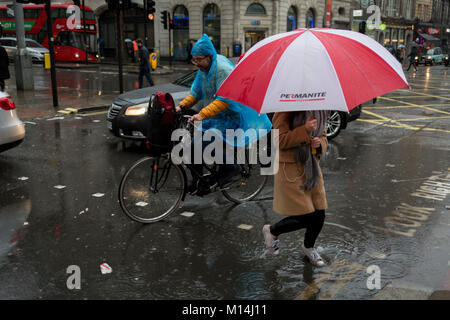 A cyclist avoids pedestrians as Storm Georgina swept across parts of Britain and in central London, lunchtime office workers were caught out by torrential rain and high winds, on 24th January 2018, in London, England. Pedestrians resorted to leaping across deep puddles at the junction of New Oxford Street and Kingsway at Holborn, the result of overflowing drains. Stock Photo
