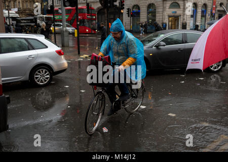 A cyclist avoids pedestrians as Storm Georgina swept across parts of Britain and in central London, lunchtime office workers were caught out by torrential rain and high winds, on 24th January 2018, in London, England. Pedestrians resorted to leaping across deep puddles at the junction of New Oxford Street and Kingsway at Holborn, the result of overflowing drains. Stock Photo