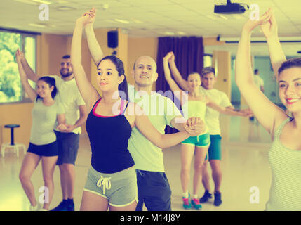 Positive couples of adults practicing salsa in modern dance studio Stock Photo