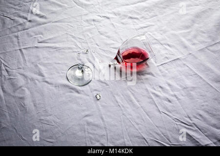 Broken glass of red wine left on a table. Stock Photo