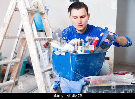 Worker repairing room and looking for necessary tool in toolbox Stock Photo