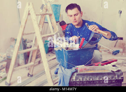 Young builder handyman choosing necessary tool in toolbox Stock Photo