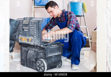professional builder handyman choosing necessary tool in toolbox Stock Photo