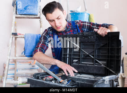 Worker repairing room and looking for necessary tool in toolbox Stock Photo