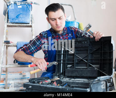 Handyman searching in his toolbox for necessary tools Stock Photo