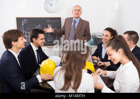 Team of engineers discussing business project and smiling indoors Stock Photo