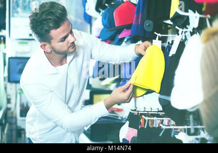 Young male customer examining knit caps in sports store Stock Photo